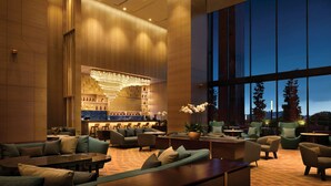 A spacious lobby with a bar area, comfortable seating, and large windows offering a view of the outdoors.