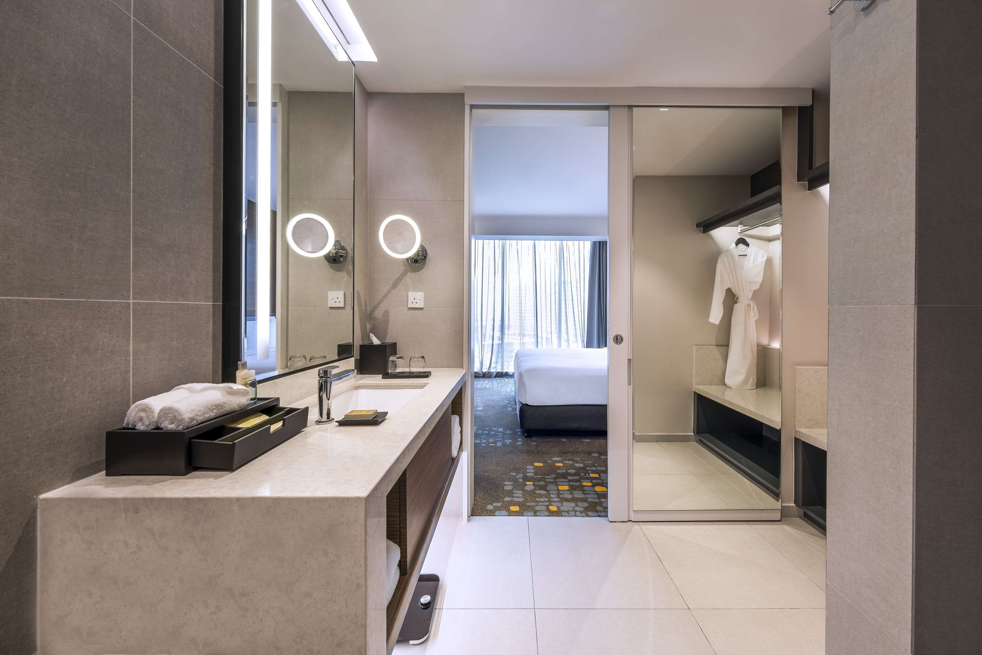 Un moderno baño de hotel con tocador, un espejo grande y un vestidor.