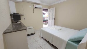 Quarto pequeno e limpo com uma cama, uma escrivaninha e uma janela.