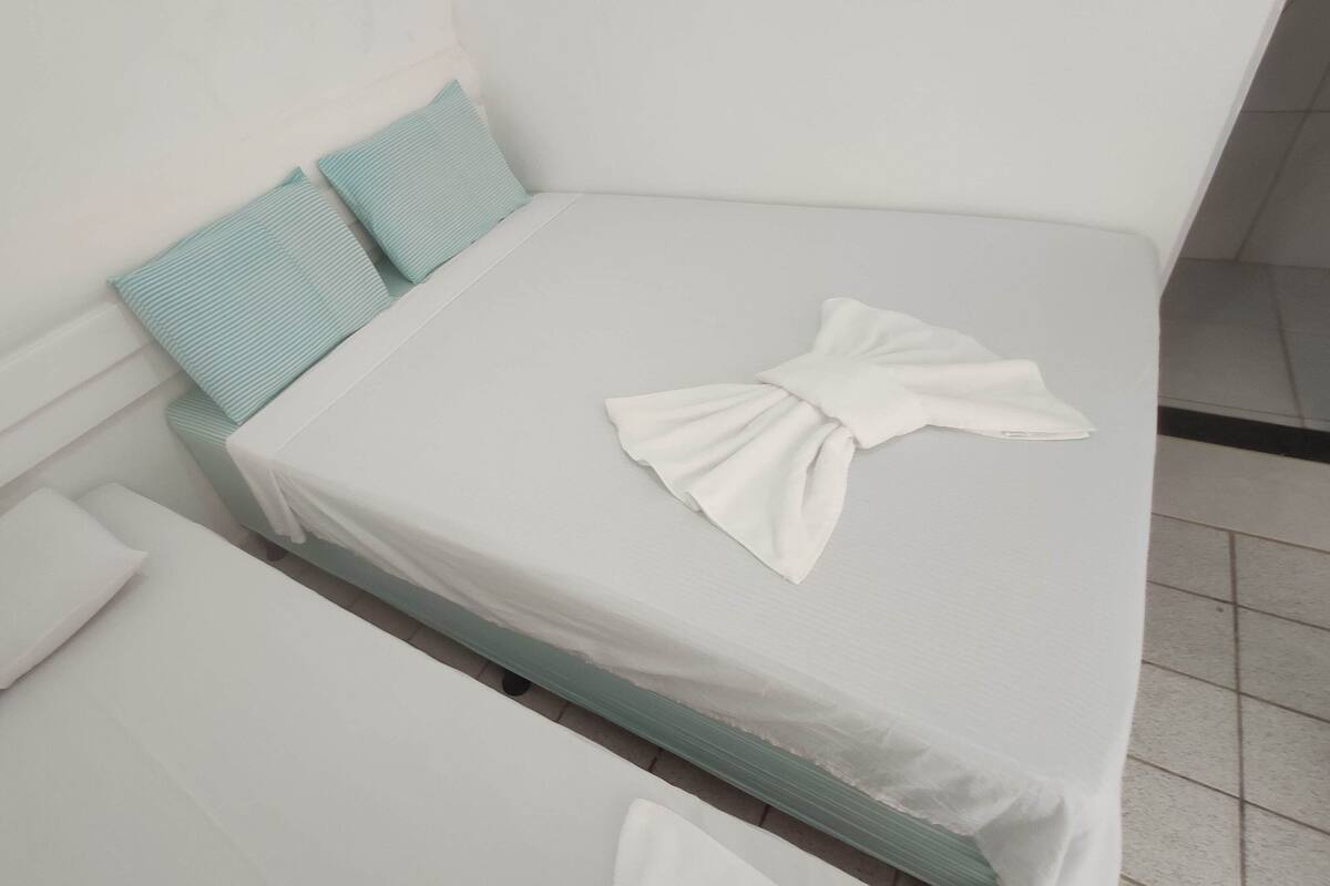 Una cama bien hecha con un colchón blanco y una manta blanca doblada.