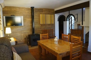 Un salon chaleureux avec un mur en bois, une cheminée, un téléviseur et un coin repas doté de meubles en bois.