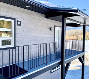 Un immeuble à la façade grise, doté d’un balcon avec une rambarde noire et d’une porte.