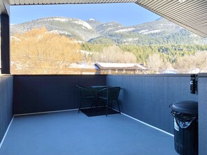 A balcony with a view of snow-covered mountains and a building in the background. - Mountainview Condo w/ Private Deck - Surrounded by Nature (Golden)