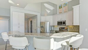 Une cuisine moderne avec des armoires blanches, un plan de travail en granit et un four encastré.