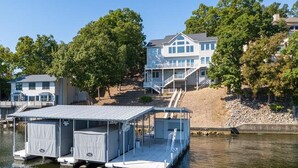 Une propriété au bord du lac, dotée d’un quai, d’un abri à bateaux et d’une grande maison avec un balcon donnant sur l’eau.