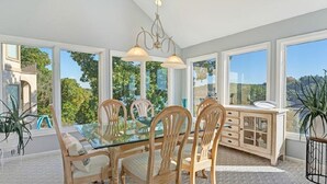 Un coin repas avec une table en verre, des chaises en bois et un meuble bas en bois clair.