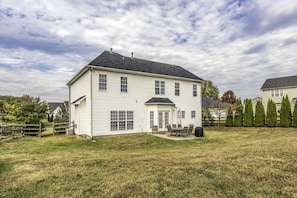 A two-story house with a front porch, a covered patio, and a fenced yard.
