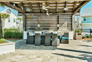 Relax in a patio with a grill, wicker chairs, and a ceiling fan.