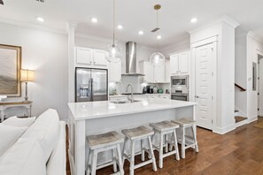 Enjoy cooking in this well-equipped kitchen with a large island, stainless steel appliances, and pendant lights above the sink.