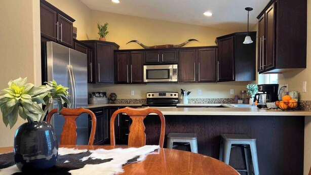 Una cocina moderna con armarios de madera oscura, electrodomésticos de acero inoxidable y una isla central con taburetes.