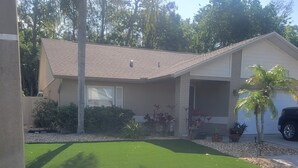 Una casa residencial con un césped cuidado, un garaje y una palmera pequeña.