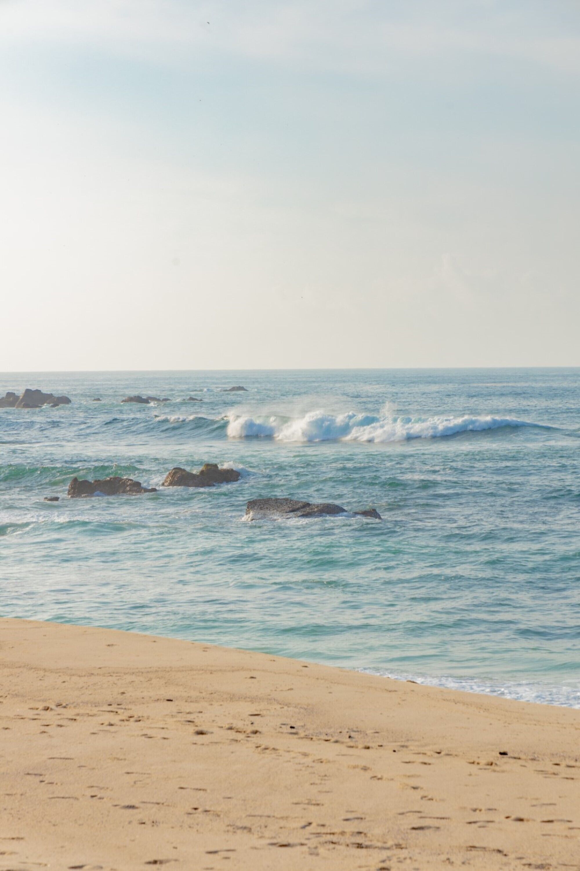 A beach with waves and rocks.