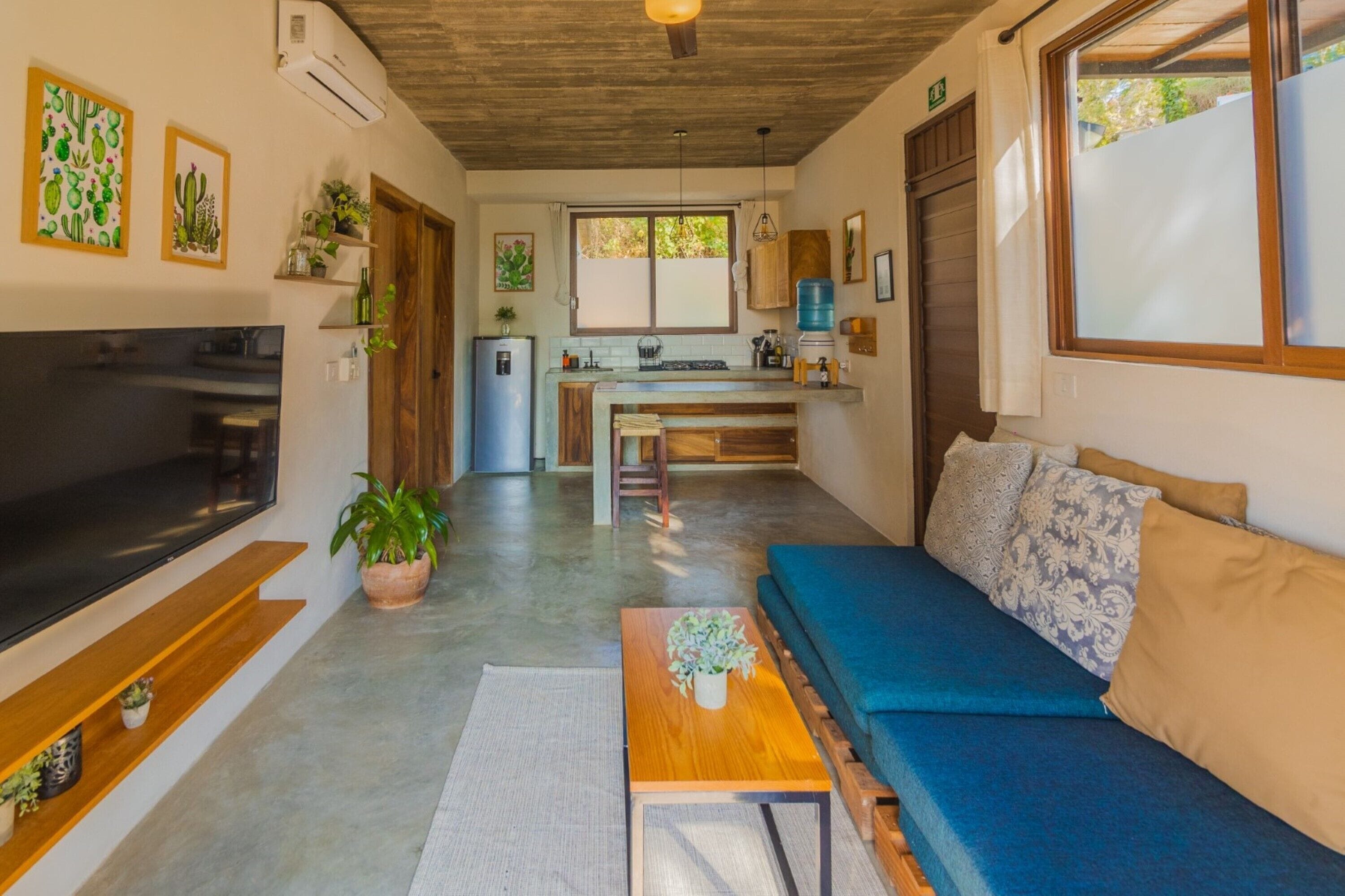 A modern living room with a flat-screen TV, a blue sofa, and a wooden coffee table.
