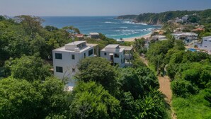 Une zone côtière avec des bâtiments modernes, une plage et une végétation luxuriante.
