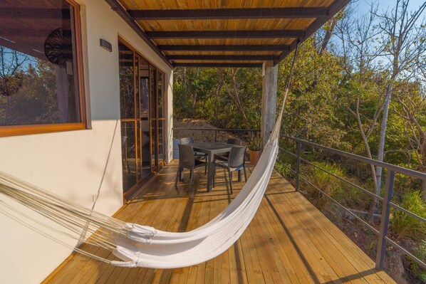 A wooden deck with a hammock, a table, and chairs.