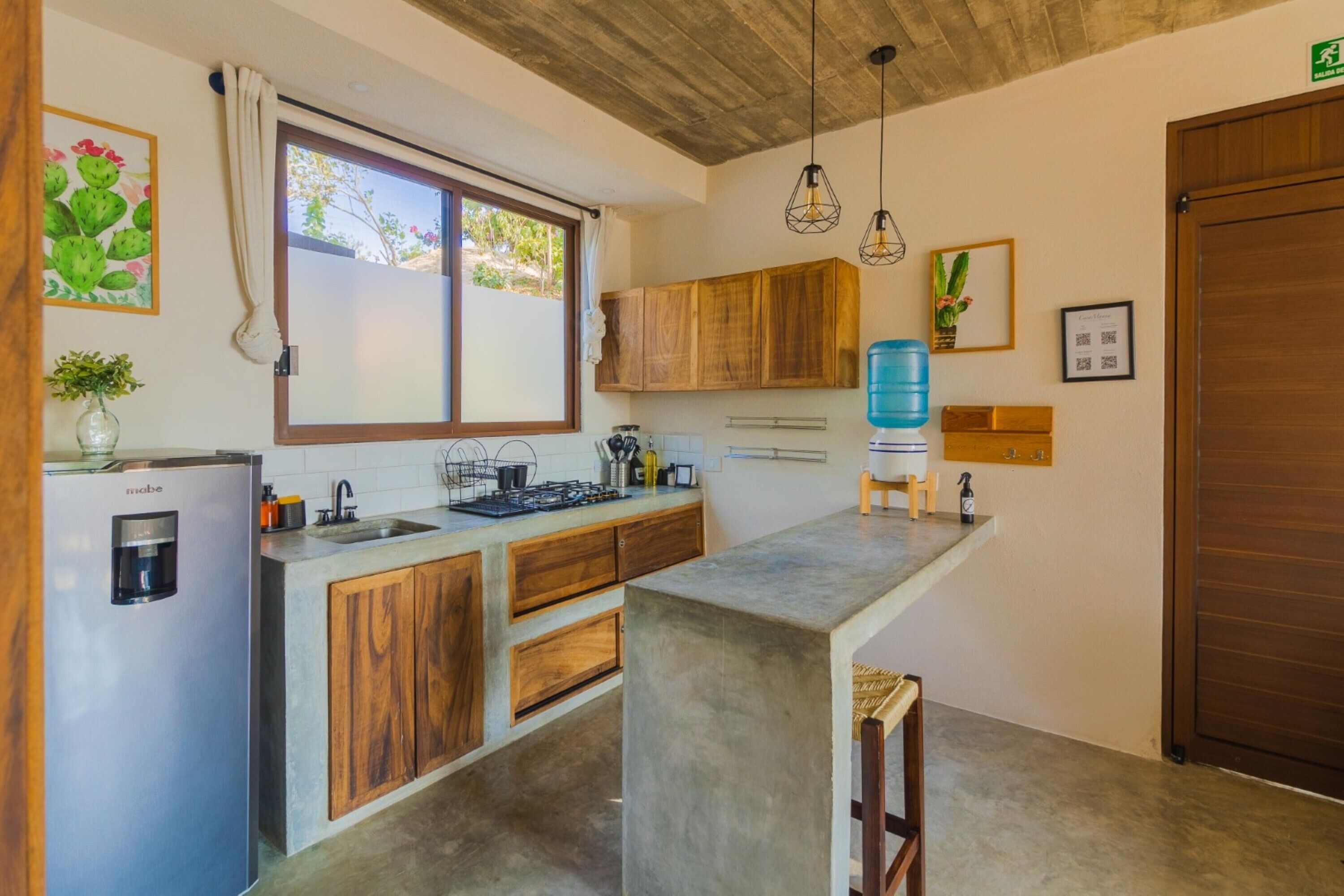 Una cocina compacta con armarios de madera, dispensador de agua integrado y una cafetera.