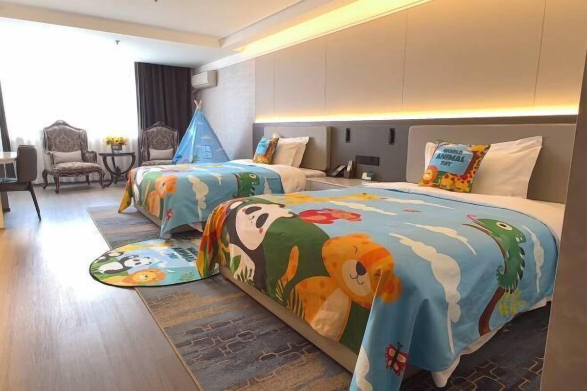 A hotel room with two beds, a desk, and a chair.