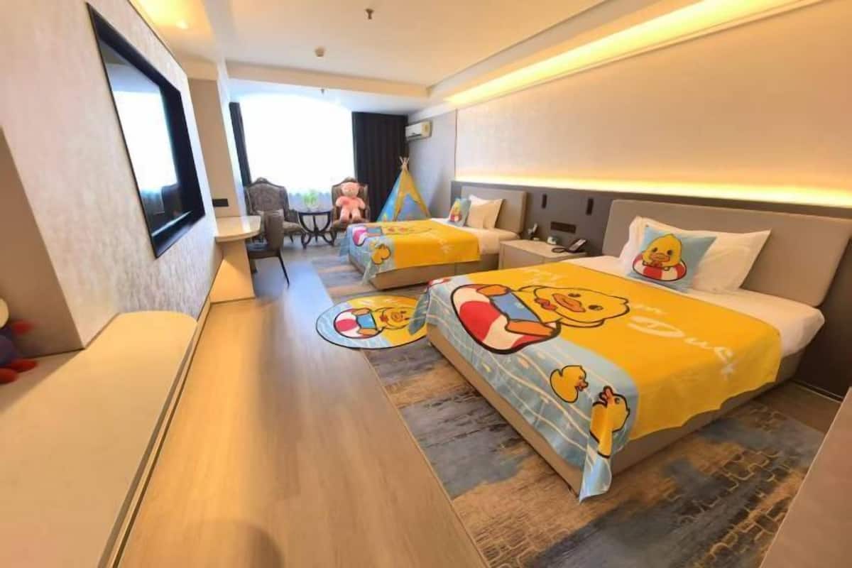 A hotel room with two beds, a desk, and a chair.