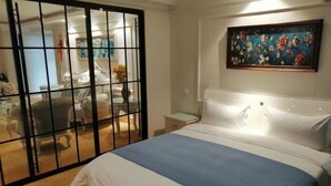 A hotel room with a large bed, a painting on the wall, and a view through a glass door. - Tianlong Hotel (Zibo)