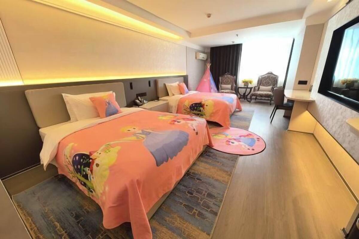 A hotel room with two beds, a sofa, a TV, and a window.