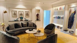 A modern living room with a gray sectional sofa, a round coffee table, and a bookshelf filled with books and decorative items. - Tianlong Hotel (Zibo)
