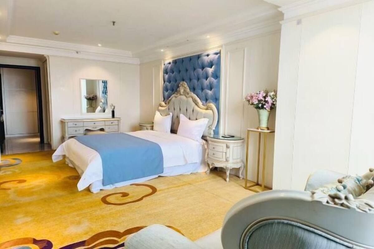 A hotel room with a large bed, a nightstand, a dresser, and a chair.