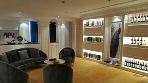A modern living room with a sofa, armchairs, and a coffee table. There are bookshelves and a wine display. - Tianlong Hotel (Zibo)