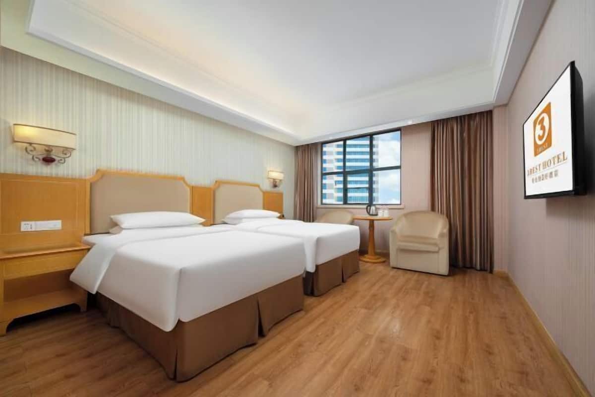 A hotel room with two beds, a desk, a chair, a TV, and a window with curtains.