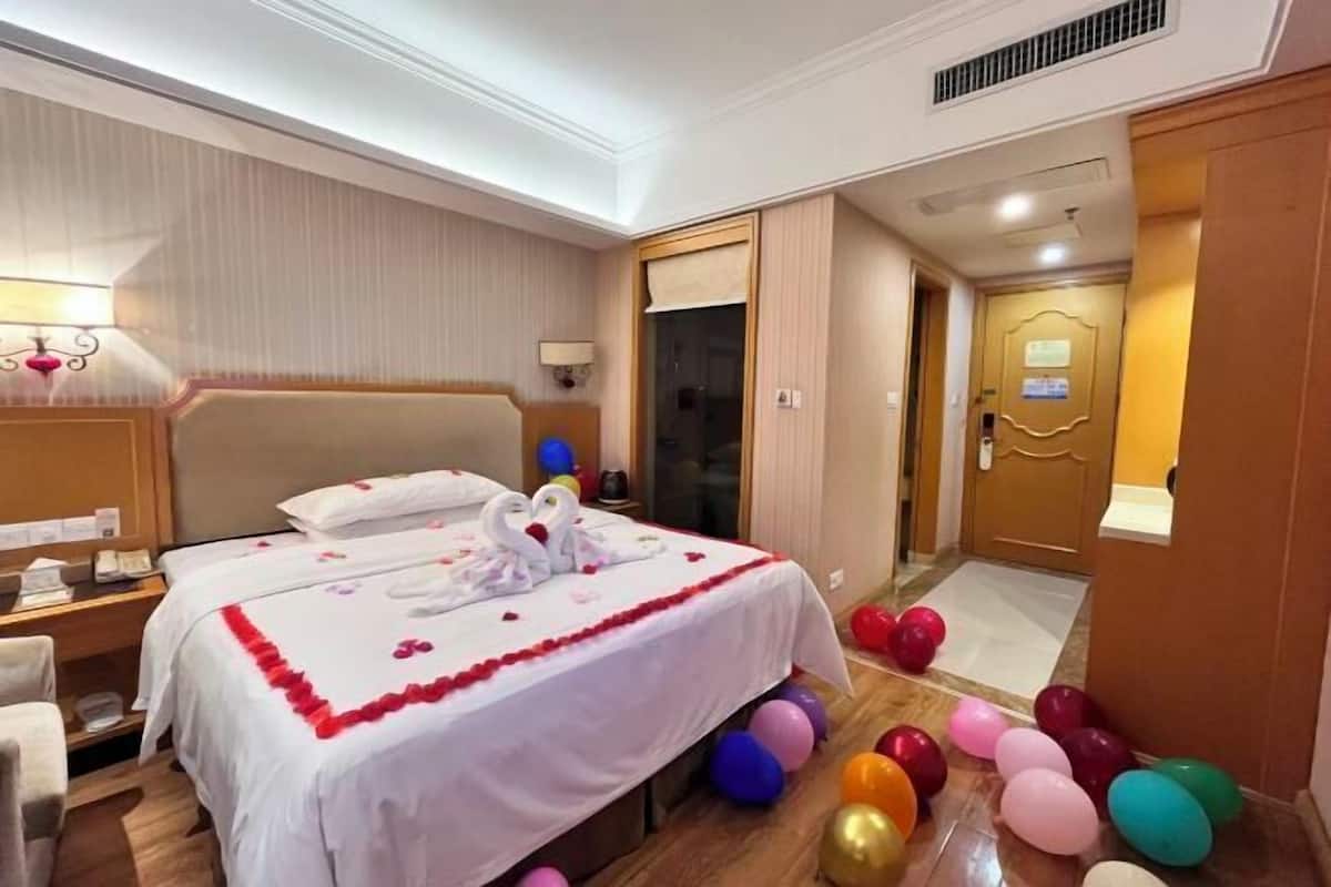 A hotel room with a large bed, a bedside table, a lamp, and a door.