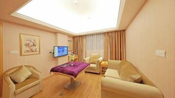 Una habitación de hotel con tragaluz, televisor de pantalla plana, sofá, sillón y una pequeña mesa.