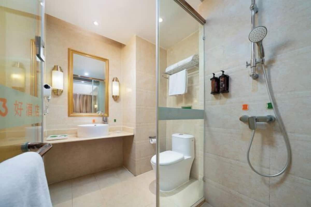 A modern bathroom with a glass shower enclosure, a sink, a toilet, and a mirror.