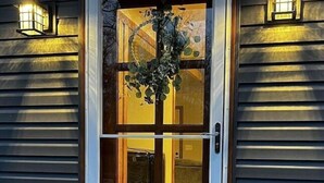 A front door with a glass panel, a wooden door frame, and a small window above it. There are two wall-mounted lights on either side of the door. - Waterfront Ranch on The Delaware River (Matamoras)