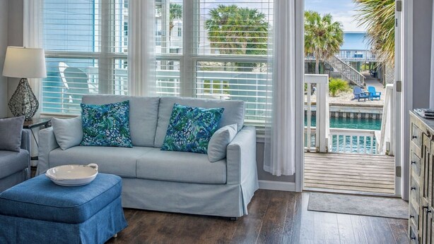 A living room with a sofa, a side table, and a view of a pool and outdoor area. - Waterfront Home, Stunning Canal Views, Deck (Navarre)