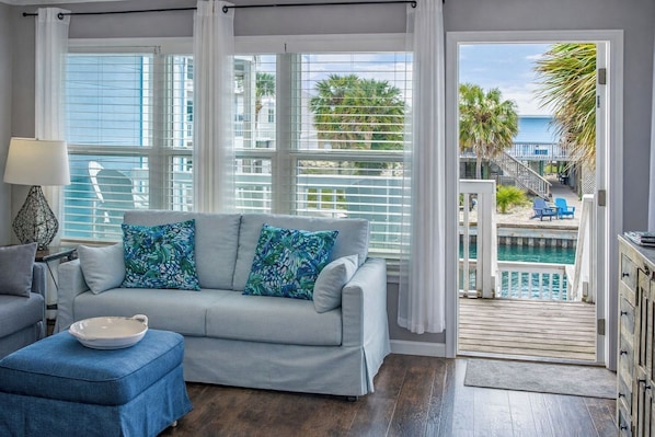 A living room with a sofa, a side table, and a view of a pool and outdoor area.