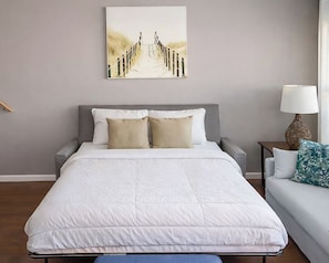 A neatly arranged bedroom with a large bed, a bedside table, a lamp, and a sofa. - Waterfront Home, Stunning Canal Views, Deck (Navarre)