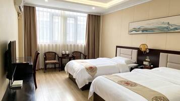 A hotel room with two beds, a desk, a chair, a TV, and a painting on the wall.