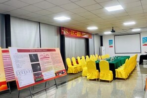 A conference room with a long table, yellow chairs, a presentation screen, and informational posters. - Zhongting Holiday Hotel (Lufeng)