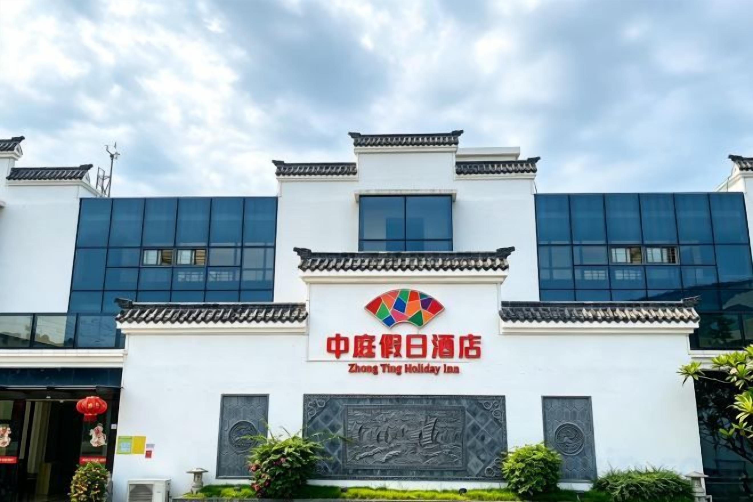 A hotel with a traditional Chinese architectural style, featuring a prominent entrance with a tiled roof and a modern glass facade.