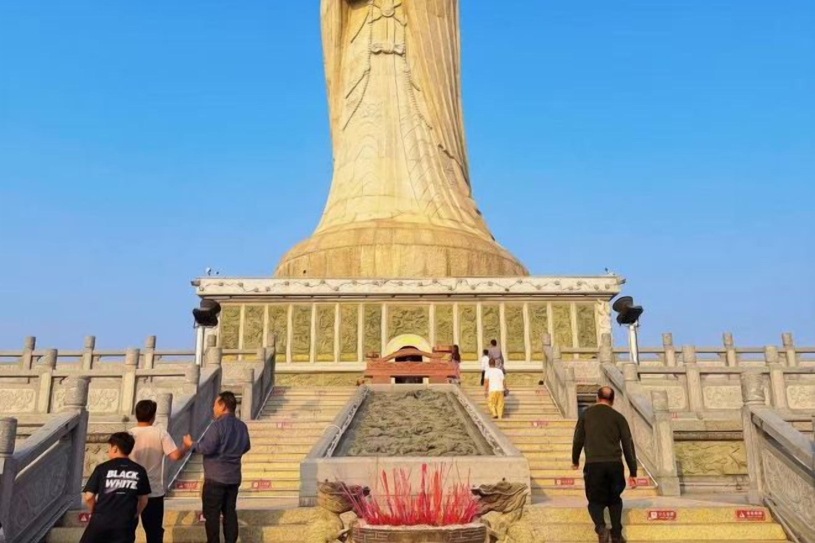 Un grande monumento cilindrico con scalini che conducono verso l'alto, circondato da una recinzione e una piccola vasca all'altezza della base.