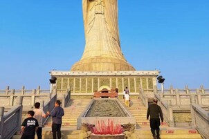 Un monumento cilíndrico grande con escalones que conducen a él, rodeado por una cerca y una pequeña piscina en la base.