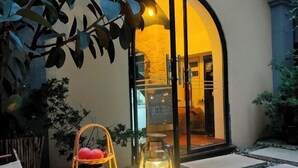 A cozy outdoor seating area with a wicker basket of fruit, a lantern, and a stone pathway leading to a building entrance. - Xile'er Hotel (Emeishan City)