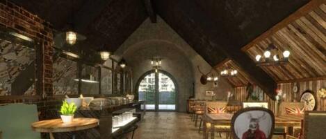 An interior with a high ceiling, exposed brick walls, and a central arched doorway. Tables and chairs are arranged for dining.