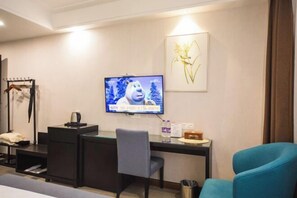 A hotel room with a desk, a chair, a television, and a bed. - Xile'er Hotel (Emeishan City)