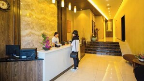 A hotel reception area with a marble wall, a reception desk, a staircase, and a reception counter. - Xile'er Hotel (Emeishan City)