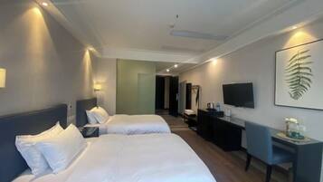 Ett hotellrum med två sängar, ett skrivbord, en TV och ett stort konstverk med ett ormbunnsmotiv på väggen.