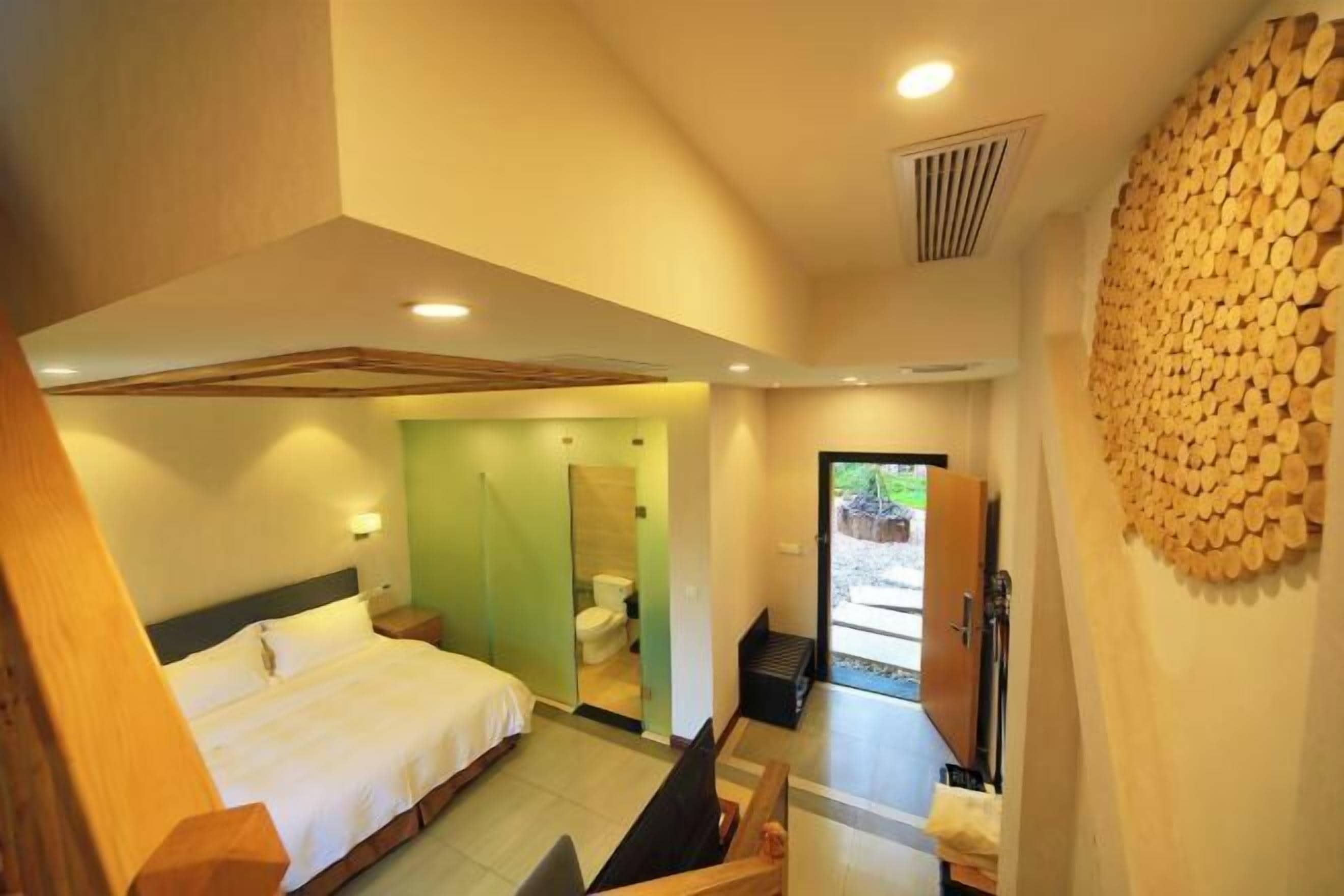 A modern hotel room with a bed, a bathroom, and a view of the outdoors.