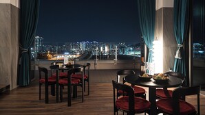 A dining area with a city view, featuring a table set with plates, glasses, and a bottle. - ACT Hotel (Daegu)
