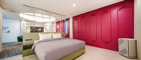 A modern hotel room with a large bed, a bedside table, a nightstand, a wall-mounted air conditioner, and a patterned carpet.