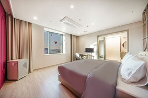 A hotel room with a large bed, a desk, a chair, and a window with a view.