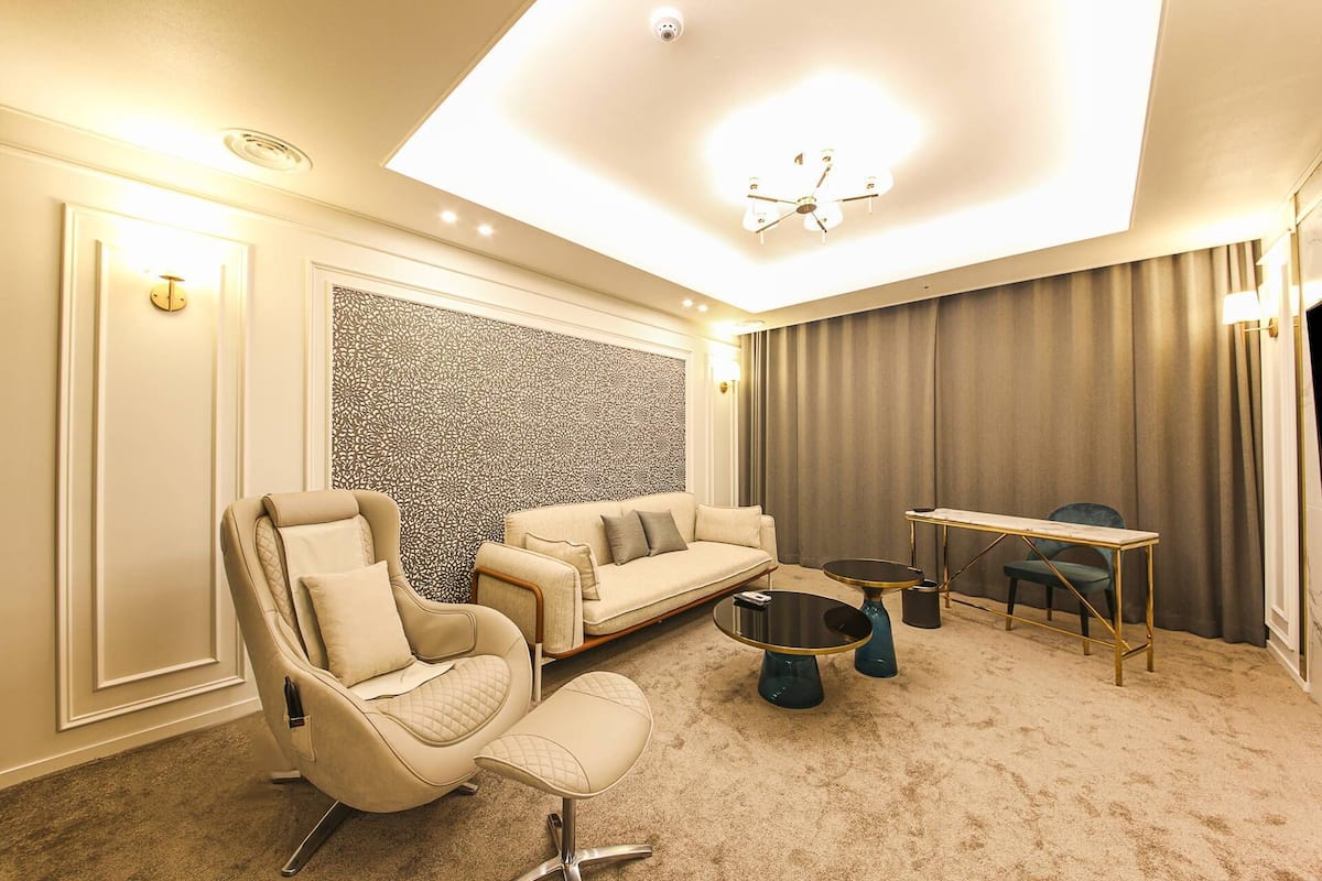A modern hotel room with a sofa, armchair, and a small table.